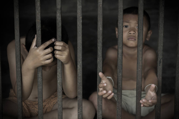 zwei Kinder halten Käfig mit traurigen und hoffnungslosen Opfern des Menschenhandels - Foto, Bild