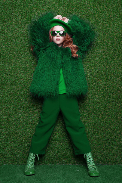 Fashion studio portrait of cute little redhead girl wearing green clothes. - Фото, изображение