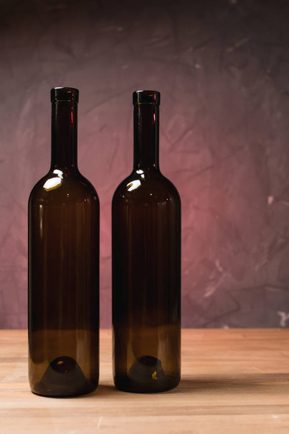 Wine bottles on the table against wooden background - Photo, Image