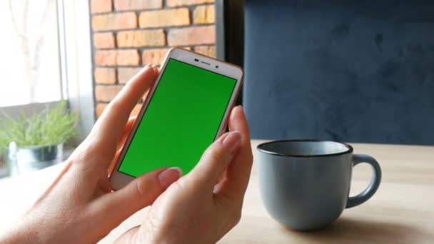 Vihreän ruudun älypuhelin. Chroma Avain valkoiseen älypuhelimeen, naisten kädet pitävät matkapuhelinta kahvilassa kahvin vieressä
 - Materiaali, video