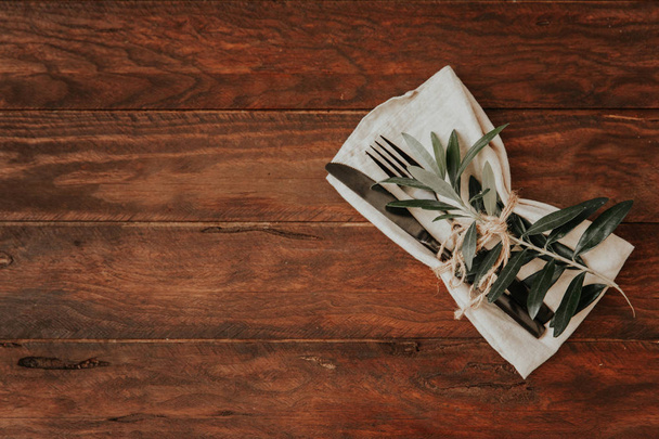 Napkin with fork, knife and fresh branch on wooden table - Fotografie, Obrázek