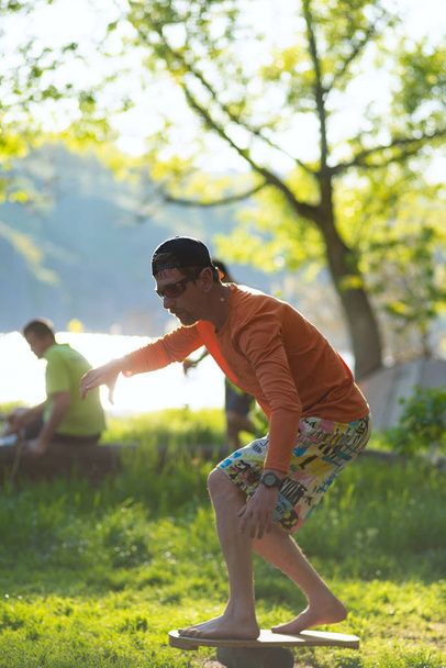 Man barefoot is training on balance board on green meadow - Foto, immagini