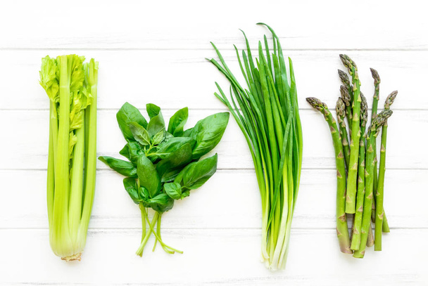 Hierbas y verduras frescas verdes sobre fondo de madera blanca. Piso laico, fondo eco vegano
 - Foto, Imagen