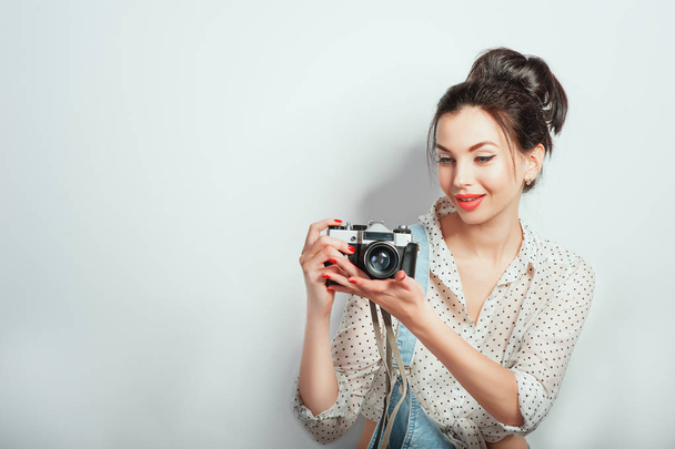 Fashion look, pretty cool young woman model with retro camera wearing in denim clothes posing on white wall. Expressive beauty girl photographer holding photocam. Emotions Lifestyle People concepts - Fotó, kép