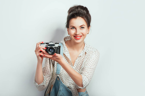 Divat néz ki, szép hűvös fiatal nő modell retro fényképezőgép viselt farmer ruha pózol a fehér fal. Kifejező szépség lány fotós gazdaság photocam. Érzelmek emberek életmód fogalmak - Fotó, kép