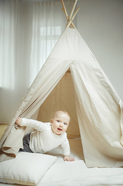 Criança curiosa espreita para a tenda das crianças cheia de travesseiros
 - Foto, Imagem