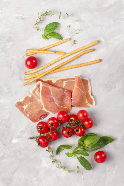 Bunch of fresh basil, tomatoes, ham and olive oil - traditional ingredient of italian cuisine - Foto, afbeelding