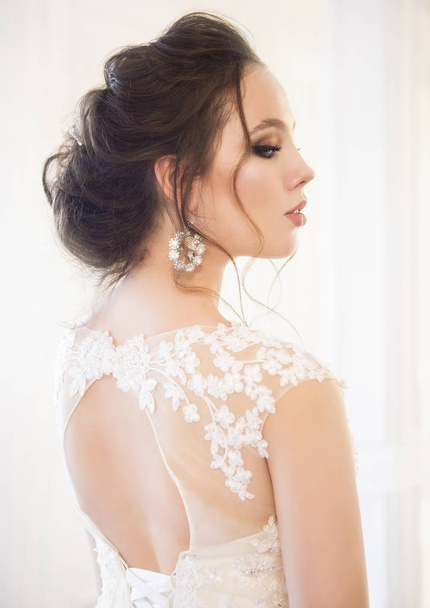 Красива брюнетка з букетом позує у весільній сукні
  - Фото, зображення