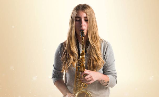 Fille jouer le saxophone sur fond ocre
 - Photo, image