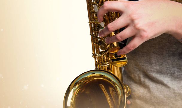 Girl playing the saxophone on ocher background - Foto, afbeelding