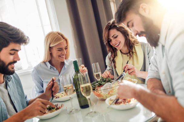 Freunde essen zu Hause zu Mittag, genießen zusammen. Menschen, Spaß, Glück, Essen und Trinken Konzept. - Foto, Bild