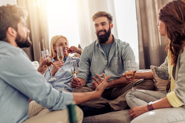 Groep vrienden hebben geweldige tijd samen thuis, drinken van wijn. - Foto, afbeelding