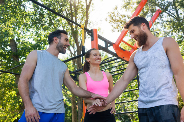 Üç neşeli genç arkadaşlar birlikte azim ve sokak egzersiz birlikte yaz aylarında başlamak için motivasyon bir jest olarak ellerini koyarak düşük açılı görünüş - Fotoğraf, Görsel