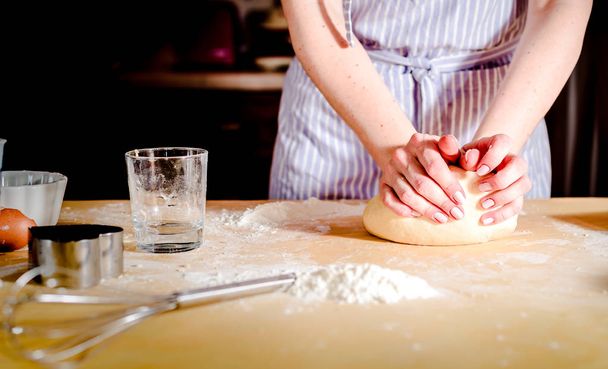 Female hands making dough on wooden table - Φωτογραφία, εικόνα