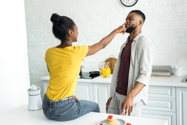 side view of african american girlfriend touching boyfriend nose at kitchen - Fotoğraf, Görsel