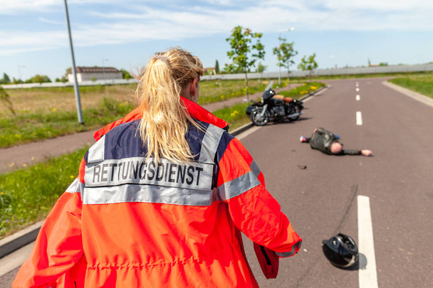 Μια γερμανική παραϊατρικό βοηθά ένα τραυματισμένο μοτοσικλετιστή. Απόφαση Rettungsdienst είναι η γερμανική λέξη για την υπηρεσία ασθενοφόρων. - Φωτογραφία, εικόνα