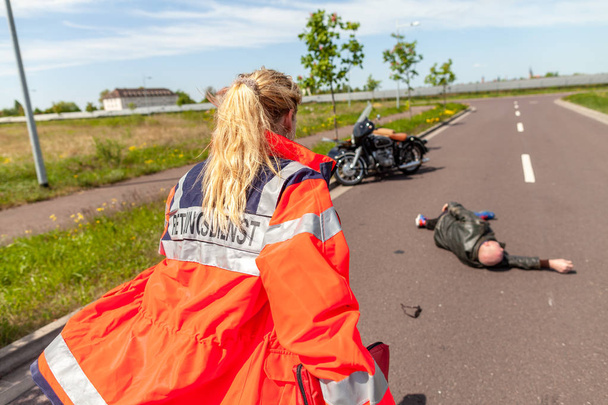 Немецкий парамедик помогает травмированному мотоциклисту. Мбаппе - немецкое слово для скорой помощи
. - Фото, изображение