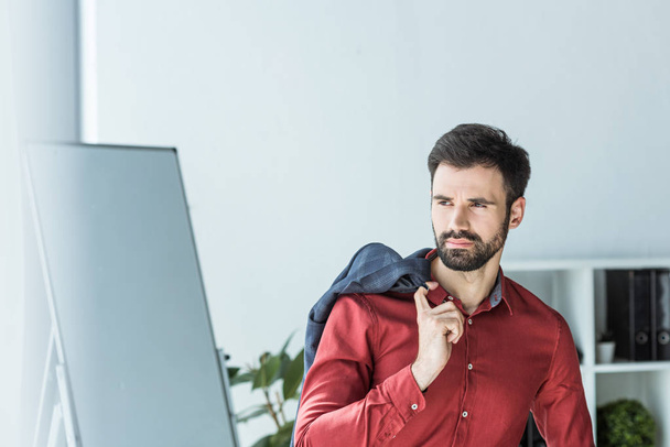 jovem empresário atraente com jaqueta no ombro no escritório
 - Foto, Imagem