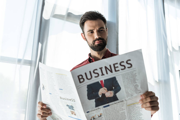 vista inferior de joven hombre de negocios guapo leyendo periódico
 - Foto, Imagen