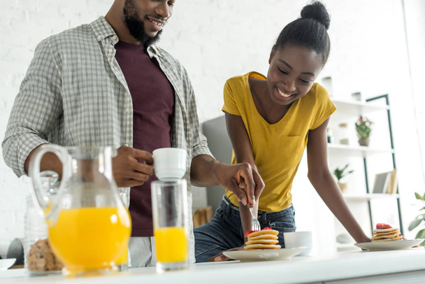cropped image of african american boyfriend taking pancakes with fork at kitchen - Foto, imagen