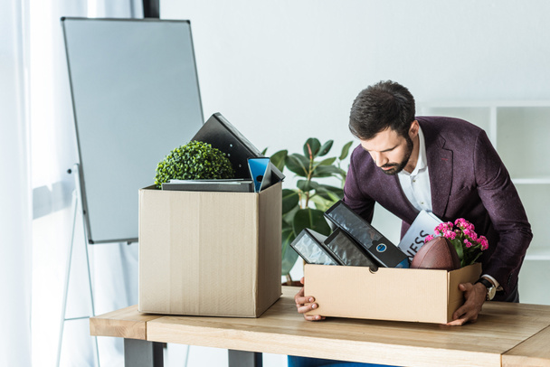 fired businessman taking box of personal stuff from desk at office - Fotografie, Obrázek