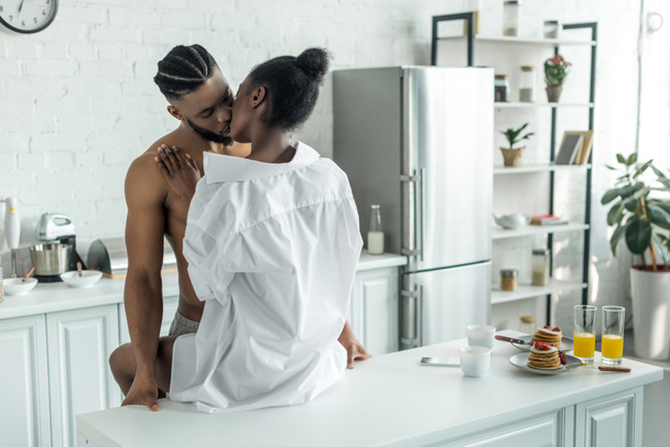 seductive african american couple kissing on kitchen counter at kitchen - Foto, afbeelding
