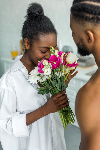 african american girlfriend sniffing flowers at kitchen - Фото, изображение