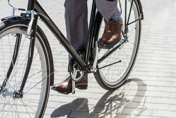 Schnappschuss eines Geschäftsmannes in klassischen Schuhen auf einem Oldtimer-Fahrrad - Foto, Bild
