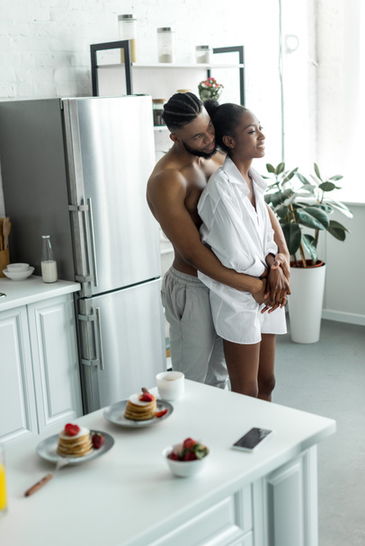 african american couple hugging at kitchen - Фото, изображение