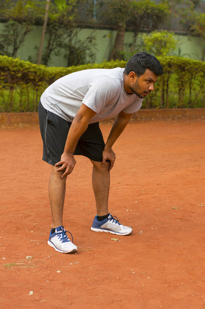 Jeune homme appuyé sur ses genoux après le jogging
 - Photo, image