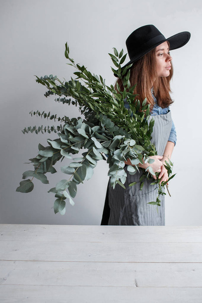 Florist makes a bouquet. Process of work. woman holding a bouquet of eucalyptus in hands - 写真・画像