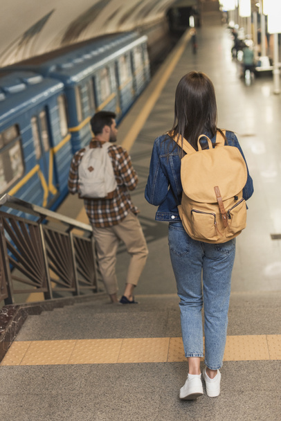 πίσω όψη του κομψό ταξιδιώτες με Σακίδια πηγαίνοντας κάτω στο σταθμό του μετρό  - Φωτογραφία, εικόνα