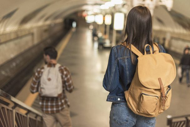visão traseira de viajantes com mochilas descendo na estação de metrô
  - Foto, Imagem