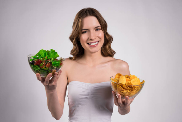Girl is holding bowl of salad and chips isolated. - Foto, Imagen