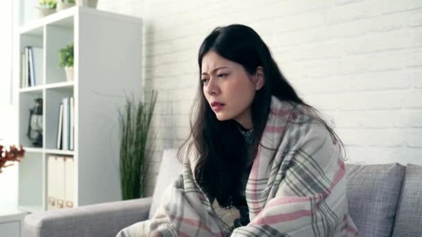 Dolly záběr asijské ženy, které trpí bolestí hlavy sedí na pohovce v obývacím pokoji doma. koncept životní styl a zdraví. - Záběry, video