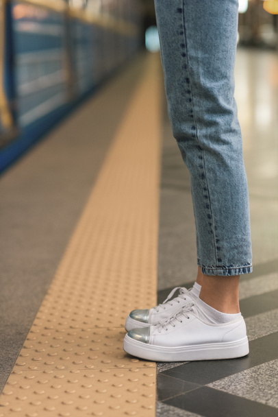 cropped image of female legs in stylish jeans and sneakers at subway station  - Fotoğraf, Görsel