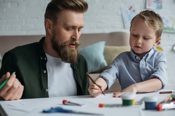 apa és aranyos kis fia, színes ceruza rajz képeket együtt otthon - Fotó, kép