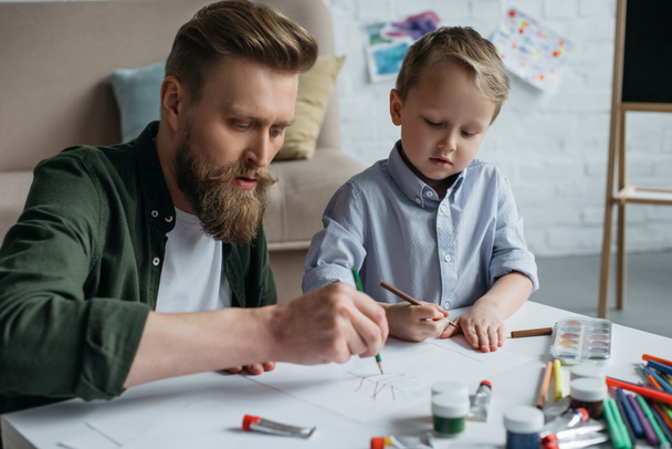 父と家庭で一緒に絵を描くカラフルな鉛筆とかわいい息子 - 写真・画像