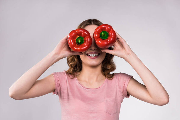 Playfull girl posing with red peppers isolated. - Φωτογραφία, εικόνα