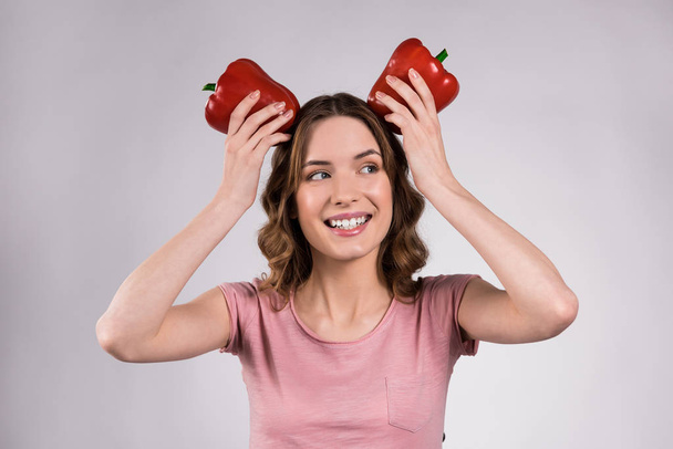 Playfull girl posing with red peppers isolated. - Photo, Image