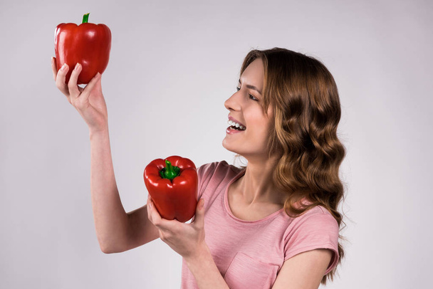 Playfull girl posing with red peppers isolated. - Valokuva, kuva