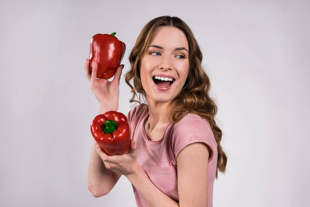 Playfull girl posing with red peppers isolated. - Фото, зображення