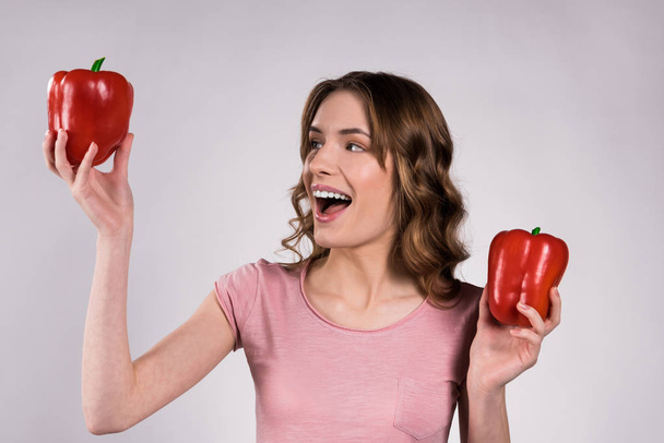 Happy girl posing with red peppers isolated. - Fotó, kép