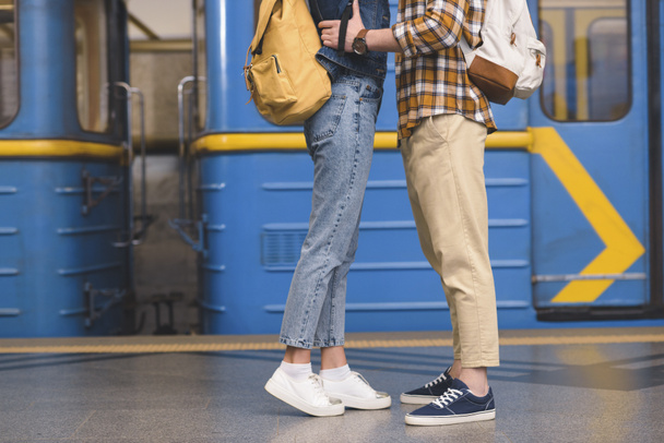 abgeschnittenes Bild von stylischem Touristenpaar, das sich an U-Bahn-Station umarmt  - Foto, Bild