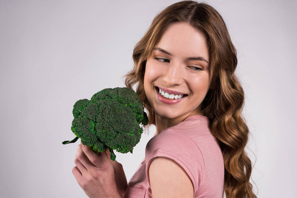 Happy girl posing with broccoli isolated. - Фото, изображение