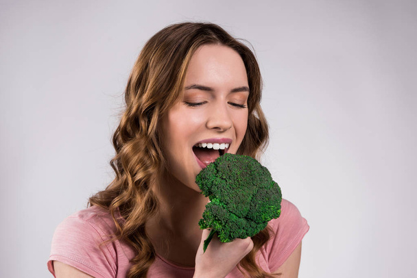 Smiling girl posing with broccoli isolated. - 写真・画像