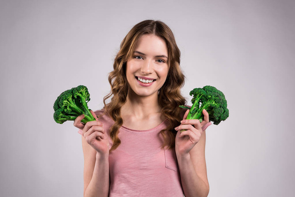 Smiling girl posing with broccoli isolated. - Foto, Imagen