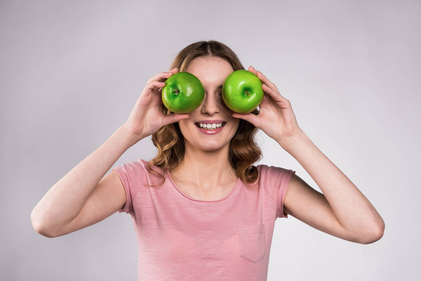 Ευτυχισμένος κορίτσι ποζάρει με πράσινα μήλα, απομονωμένο. - Φωτογραφία, εικόνα