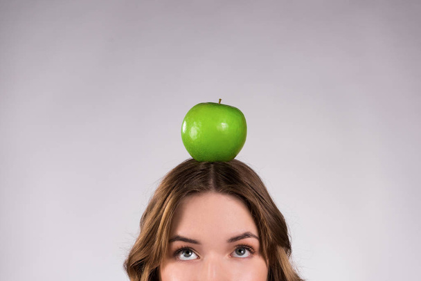 Девушка позирует с зеленым яблоком улыбается изолированно
. - Фото, изображение
