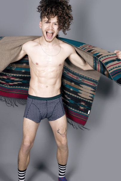 Young athletic ginger man in pancho studio portrait - 写真・画像